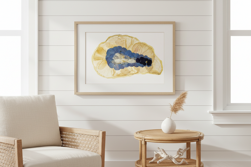 Decorative wall art with a pressed fl,ower oyster in a gold frame.