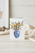 Greeting card with a blue and white vase holding flowers on a white background