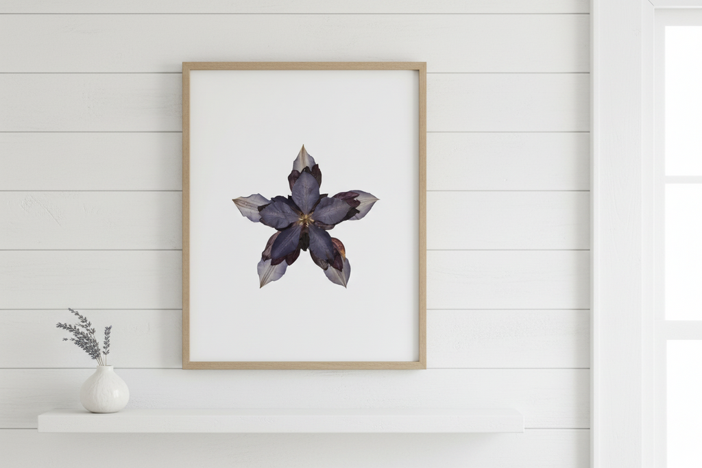 Framed artwork of a pressed flower with a gold frame on a white background