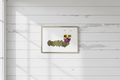 Decorative arrangement of pressed flowers and leaves to create a caterpillar in a frame on a white background