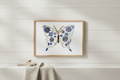 Butterfly-shaped artwork made of pressed flowers with a gold frame.