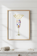 Framed artwork of a champagne glass made with pressed flowers  on a white background