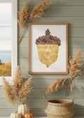 A dried botanical art piece shaped like an acorn, featuring a textured golden-yellow lower section made of overlapping petals, a band of purple and brown tiny flowers at the top, and a single brown leaf at the very tip, all isolated on a white background.
