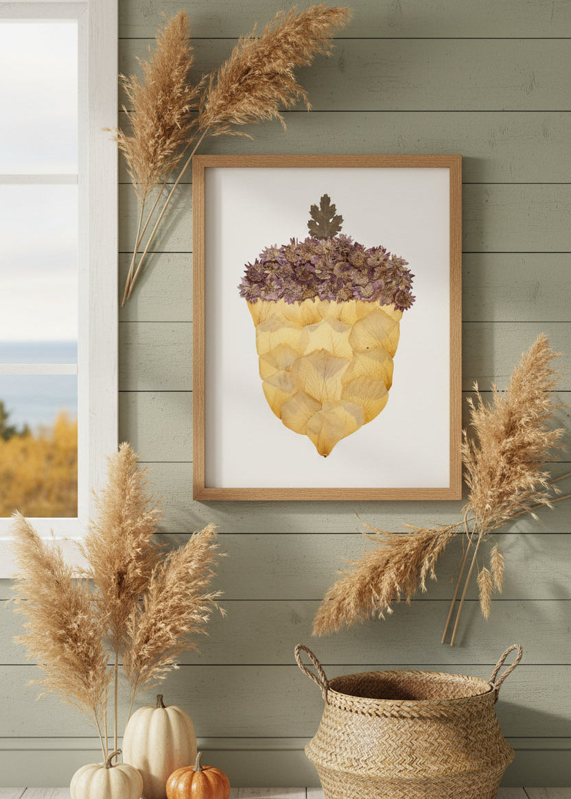 A dried botanical art piece shaped like an acorn, featuring a textured golden-yellow lower section made of overlapping petals, a band of purple and brown tiny flowers at the top, and a single brown leaf at the very tip, all isolated on a white background.