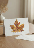 A single dried autumn maple leaf with mottled golden yellow, orange, and reddish-brown tones, isolated on a plain white background.