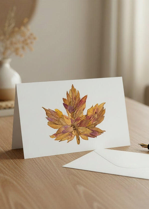 A single dried autumn maple leaf with mottled golden yellow, orange, and reddish-brown tones, isolated on a plain white background.