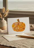 An autumn-themed decorative pumpkin crafted from layered dried orange and yellow leaves, featuring a textured stem at the top, isolated on a white background.