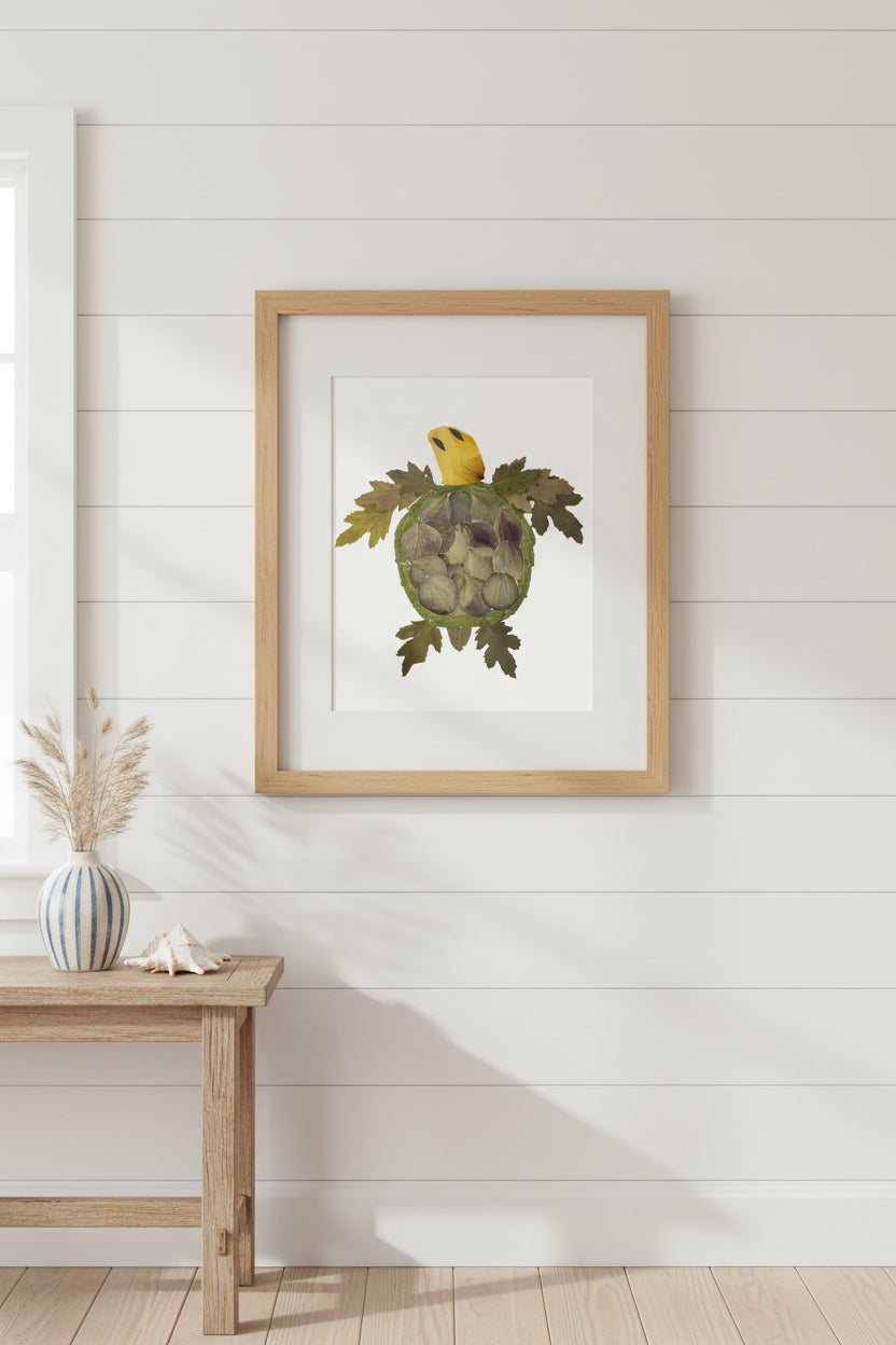 A pressed flower turtle crafted with green leaves for the shell and limbs, and a yellow rose petal head, shown on a plain white background.